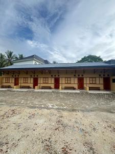 a large building with red doors and a cloudy sky at Loko Stay Syariah in Krui