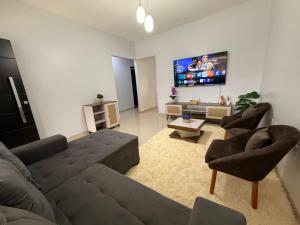 a living room with a couch and chairs and a flat screen tv at Casa Aconchego Lar in Rio Verde