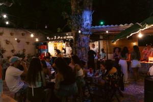 a group of people sitting in a restaurant at night at Clan.Destino Hostel in Ilhabela