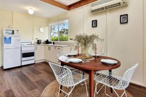 a kitchen and dining room with a wooden table and chairs at The Meadow Suite in Pokolbin +3 photos