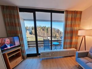a living room with a tv and a balcony at Studio Roswitha mit Pool und Sauna in Freyung