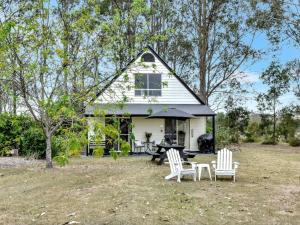 a white house with a picnic table and chairs at The Orchard Suite in Pokolbin