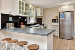 a kitchen with white cabinets and a counter with stools at The Ridge Stables in Pokolbin