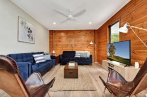 a living room with a blue couch and a flat screen tv at The Ridge Stables in Pokolbin