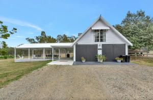 a white house with a porch and a driveway at The Ridge Stables in Pokolbin