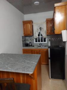 a kitchen with wooden cabinets and a black refrigerator at Sotera's Guest House in Corozal