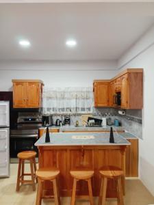a kitchen with wooden cabinets and a island with stools at Sotera's Guest House in Corozal