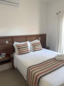 a bedroom with a large bed with white sheets and pillows at Apê Charm Jeri in Jericoacoara