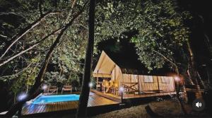 a cabin in the woods at night with a swimming pool at Bandu Buana Glamping in Kuala Pilah +10 photos