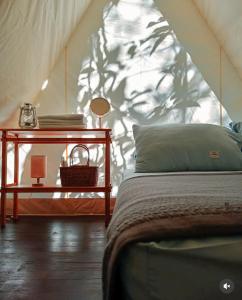 a bedroom with a bed and a table with a lamp at Bandu Buana Glamping in Kuala Pilah