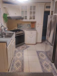 a kitchen with white cabinets and a black refrigerator at Cozy Stays in Oranjestad +8 photos