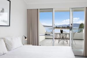 a bedroom with a bed and a balcony with a table at Horizons Lake Jindabyne in Jindabyne +63 photos