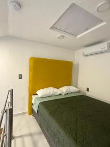 a bedroom with a green bed with a yellow headboard at Urban Loft Hotel Federalismo in Guadalajara