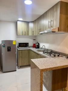 a kitchen with a stainless steel refrigerator and wooden cabinets at Urban Loft Hotel Federalismo in Guadalajara