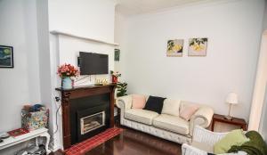 a living room with a couch and a fireplace at Comfortable Victorian Terrace close to shops in Lithgow +2 photos