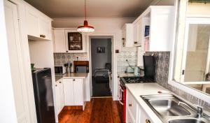 a kitchen with white cabinets and a black refrigerator at Comfortable Victorian Terrace close to shops in Lithgow