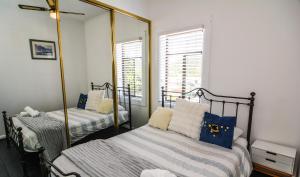 a bedroom with two beds and a mirror at Comfortable Victorian Terrace close to shops in Lithgow