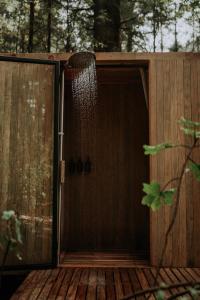 a shower in a wooden building with a door at WANDER Cabins Villa Alpina in Villa Alpina +2 photos