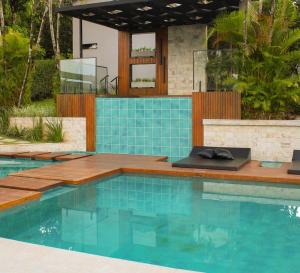 a swimming pool with blue tile and a house at Pousada Villorba in Socorro
