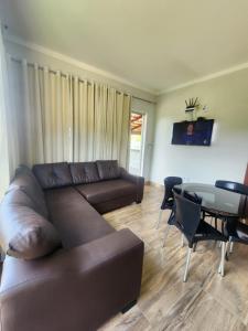 a living room with a brown couch and a glass table at Rancho paraíso verde in Capitólio