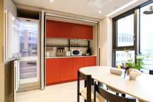 a kitchen with red cabinets and a table with chairs at ASTY Cabin Seoul Serviced Residence in Seoul