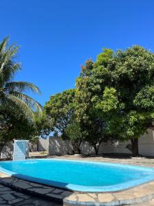 a blue swimming pool with trees in the background at Casa de praia conde in Conde +10 photos