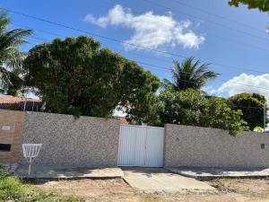 a fence with a white gate in front of a house at Casa de praia conde in Conde