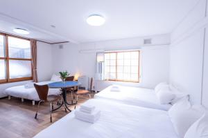 a white room with two beds and a table at Villa Blanca Yoichi in Yoichi