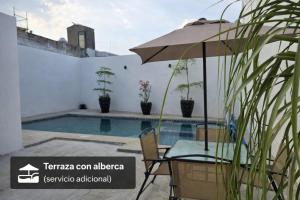 a table with an umbrella next to a swimming pool at Casa amplia para grupos Remodelada y centrica in Guadalajara