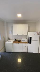 a kitchen with white cabinets and a white refrigerator at Comfortable, well-located, renovated apartment in São Leopoldo