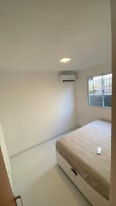 a white room with a bed and a window at Comfortable, well-located, renovated apartment in São Leopoldo