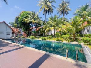 a swimming pool in front of a house with palm trees at Terrace Resort in Phú Quốc +24 photos