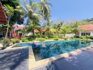 a swimming pool in front of a house with palm trees at Terrace Resort in Phú Quốc
