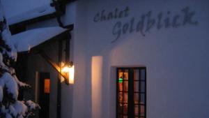 a white building with a window with a green light at Chalet Goldblick in Grächen