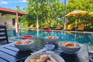 a table with bowls of food next to a swimming pool at The Son Villa Hội An in Danang