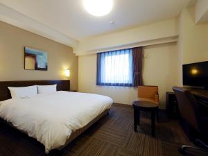 a hotel room with a bed and a desk and a window at Hotel Route-Inn Aomori Chuo Inter in Aomori