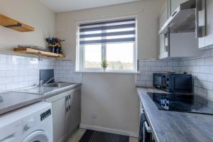 a small kitchen with a sink and a window at Anderson Apartment in Airdrie +6 photos
