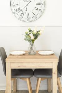 a table with a vase of flowers and a clock on a wall at Anderson Apartment in Airdrie