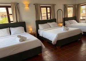 a bedroom with two beds with white sheets and a mirror at Hostel Once Once in Villa de Leyva