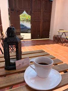 a cup of coffee sitting on a wooden table with aucer at Hostel Once Once in Villa de Leyva