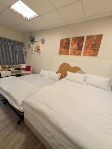 two beds in a room with white sheets at Travel Light in Tainan