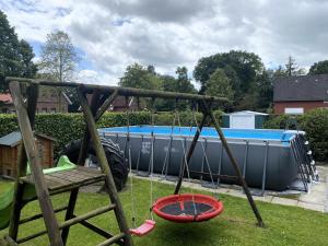 a swing set in a yard with a pool at Reihenhäuser in Strackholt in Strackholt