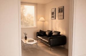 a living room with a black leather couch and a table at Sejong Hygge Stay in Sejong