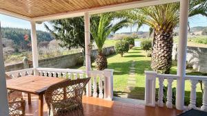 a porch with a wooden table and palm trees at The Cliffs - Casa Alecrin in O Vicedo