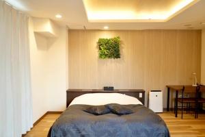 a bedroom with a bed and a painting on the wall at Hotel WILL Kashiwa in Kashiwa