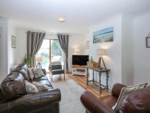 a living room with a leather couch and a television at Tŷ Gareg in Gaerwen
