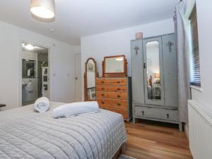 a bedroom with a bed and a dresser and a mirror at Tŷ Gareg in Gaerwen