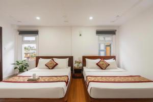 two beds in a room with two windows at Liên Hương Hotel Đà Lạt in Kon Rung (1)