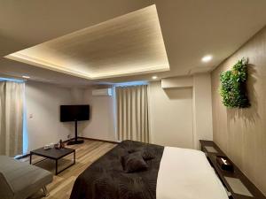a bedroom with a bed and a couch and a tv at Hotel WILL Kashiwa in Kashiwa