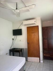 a room with a bed and a television and a door at Hostal Los Cheles in León